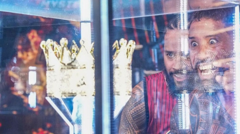 Jey Uso, accompanied by Jimmy Uso, stares into the case holding the King of the Ring crown on the stage of an episode of "WWE SmackDown."