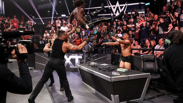DarkState hit their finisher on Saquon Shugars, as Shugars hangs in the air before crashing through the commentary desk," during an episode of "WWE NXT."