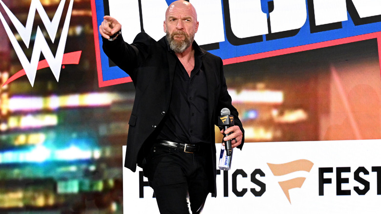 Triple H pointing while holding a microphone