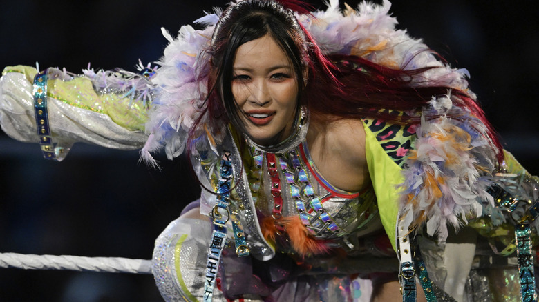 IYO SKY smirks at the camera as she hangs over the rope during her entrance.