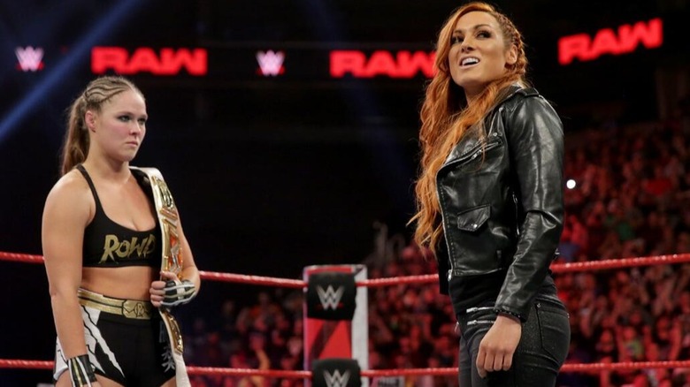 Becky Lynch takes a moment to chuckle at Ronda Rousey, who joins her in the ring
