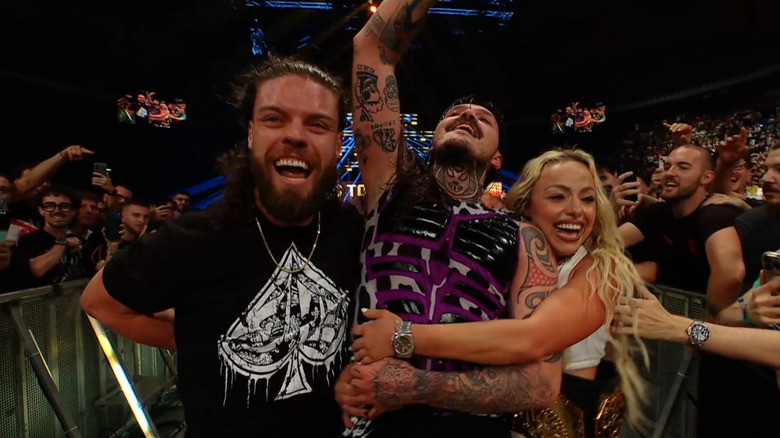Dominik Mysterio celebrates victory with JD McDonagh and Liv Morgan