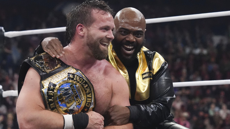 Stokely Hathaway throws his arm around Cash Wheeler, who holds one of the AEW World Tag Team Championships over his shoulder, in the ring after FTR's victory at AEW Dynasty 2026.