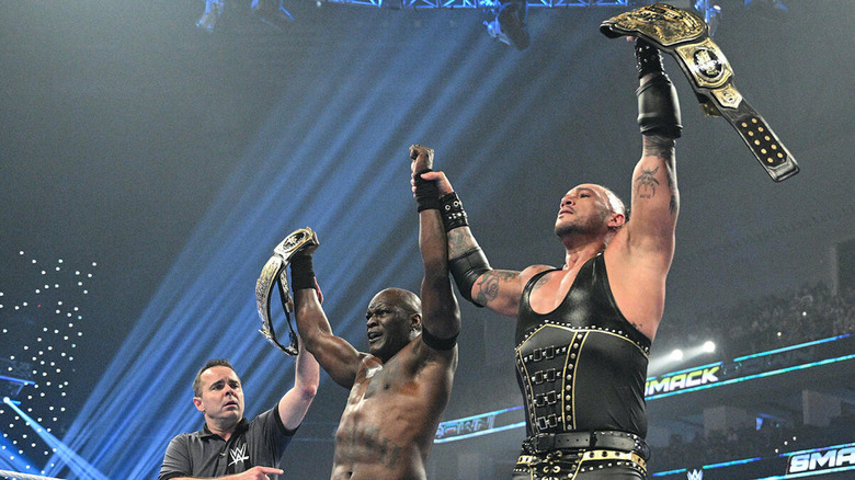 R-Truth and Damian Priest hold their titles up