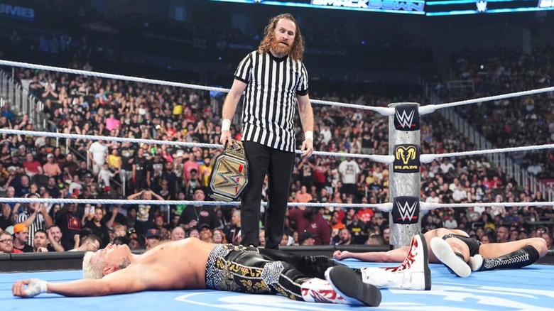 Sami Zayn stands tall, holding the Undisputed WWE Championship, over a fallen Cody Rhodes and GUNTHER in the ring after a match on the June 19, 2026 episode of 