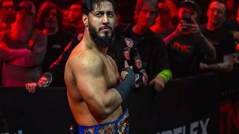 TNA International Champion Mustafa Ali hits the Order 4 taunt as he walks up the ring, title around his waist, after a match on 