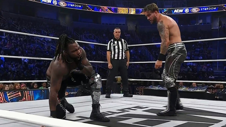 Swerve Strickland and Will Ospreay with referee Paul Turner between them