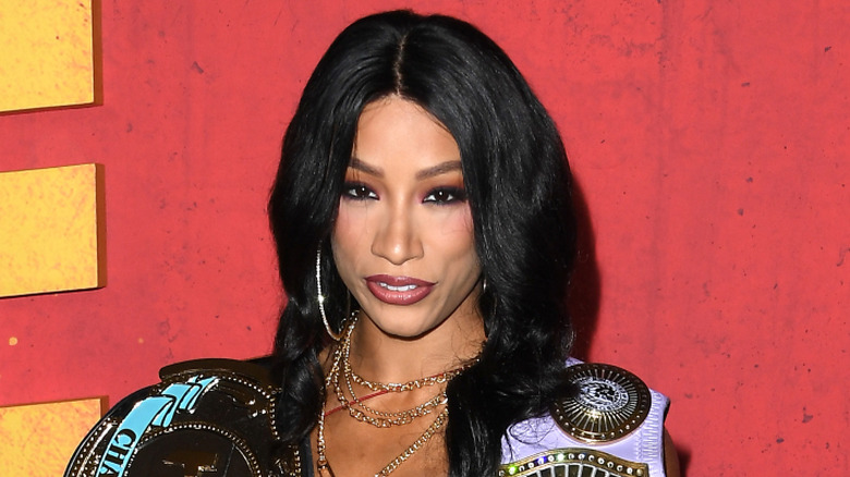 Mercedes Mone poses with two title belts that she's since lost