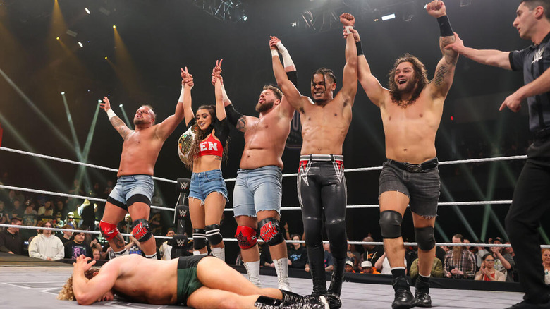 Hank and Tank, Wren Sinclair, Shiloh Hill, and EK Prosper raise their arms over a fallen Charlie Dempsey at Stand & Deliver