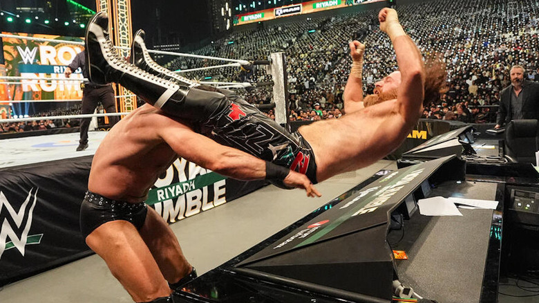 Drew McIntyre powerbombs Sami Zayn through the announce table