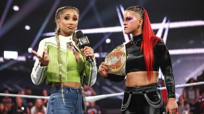Women's North American Champion Zaria stands in the ring, with the title on her shoulder, listening to Kelani Jordan cut a promo on "WWE NXT."