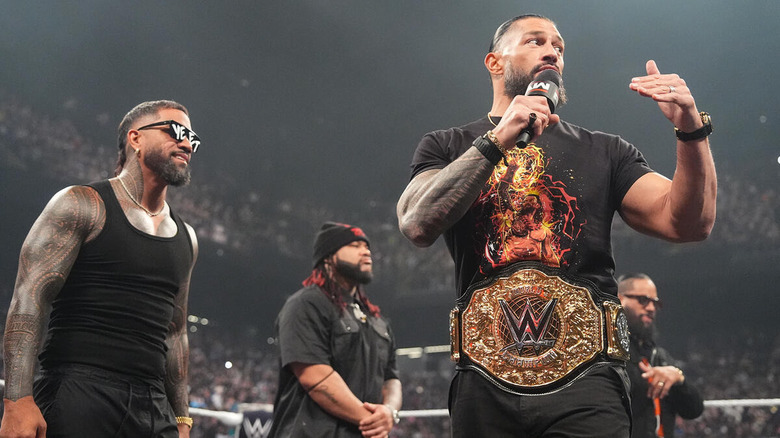 Roman Reigns with a microphone and the Bloodline by his side on "WWE Raw"