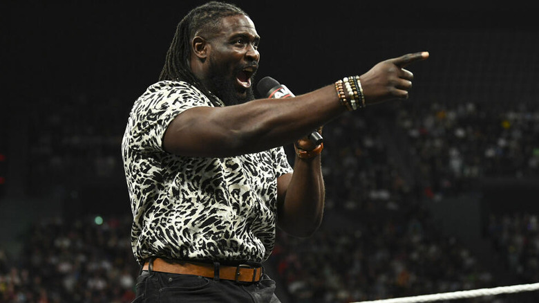 Oba Femi pointing ahead while speaking into a microphone on "WWE Raw"