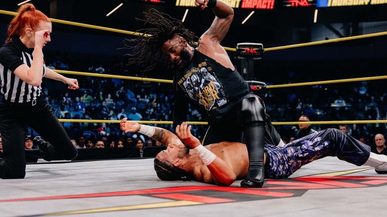 TNA X-Division Champion Cedric Alexander beats down former champion Leon Slater in the ring as a referee looks on during an episode of "TNA iMPACT."