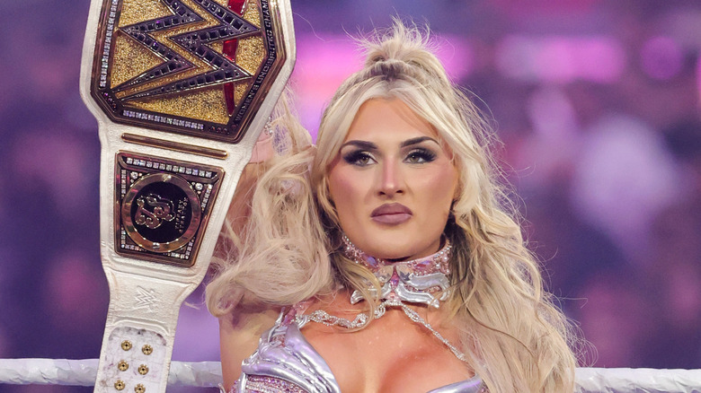 The former WWE Women's Champion Tiffany Stratton proudly holds her championship up in the air ahead of a title defense